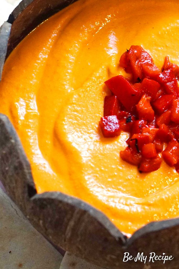 Roasted red pepper hummus showing the texture of the hummus