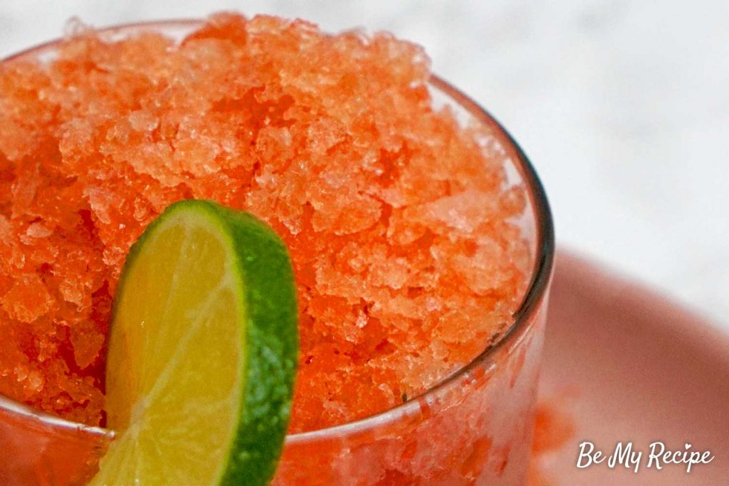 Watermelon granita in a glass with a slice of lime on the rim (up close image)
