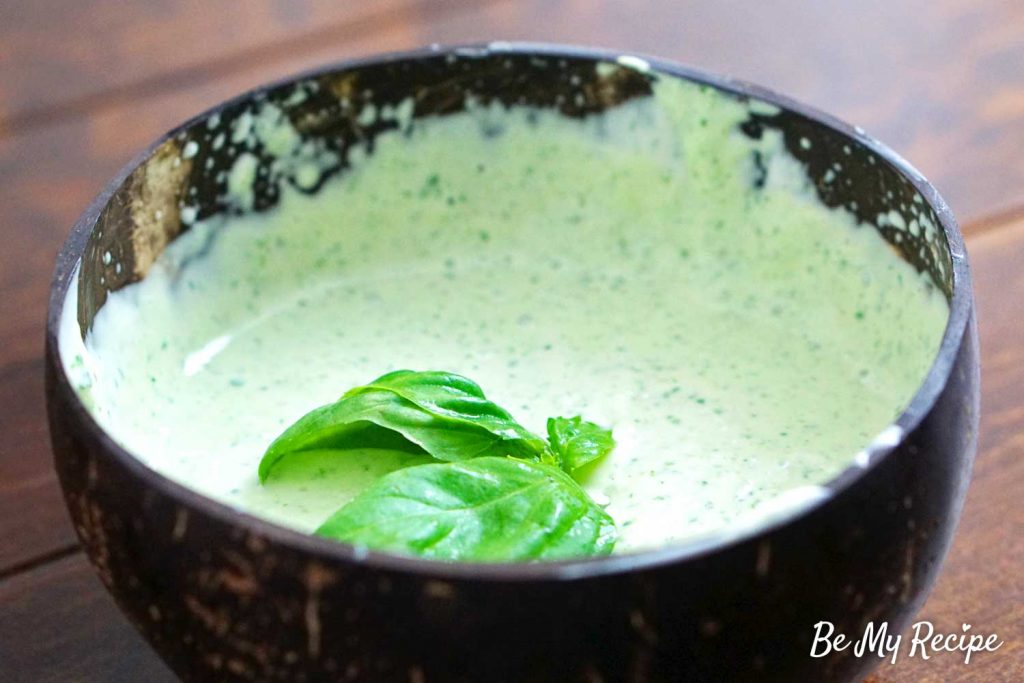 Lemon basil aioli sauce being decorated with basil leaves.