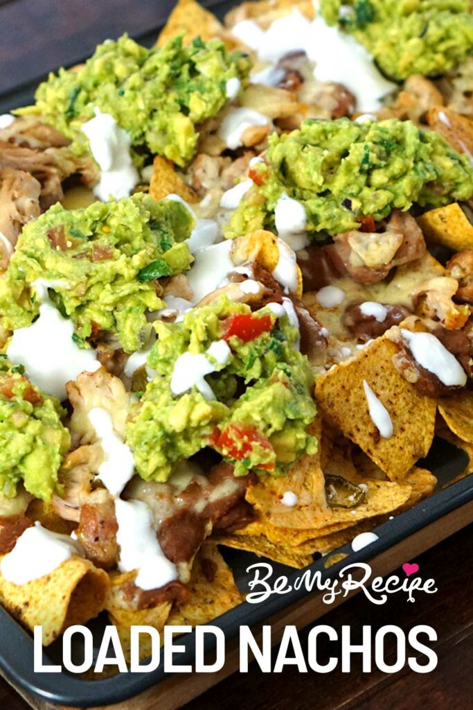Loaded nachos with refried beans, cheese, chicken, jalapenos, cilantro, guacamole, and sour cream