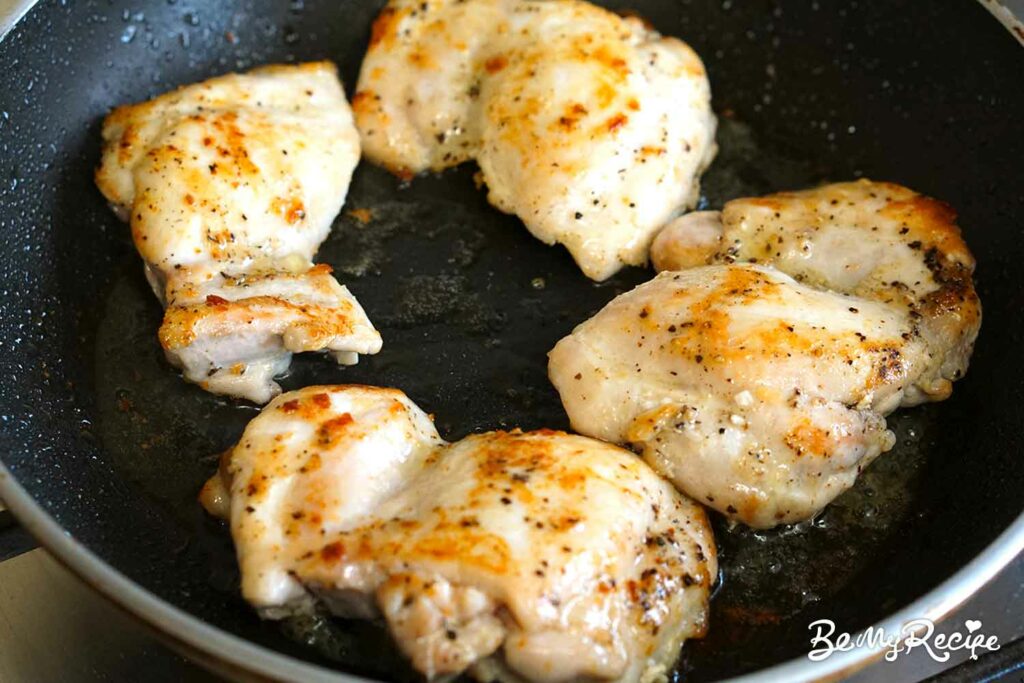 Pan-frying the chicken thighs.