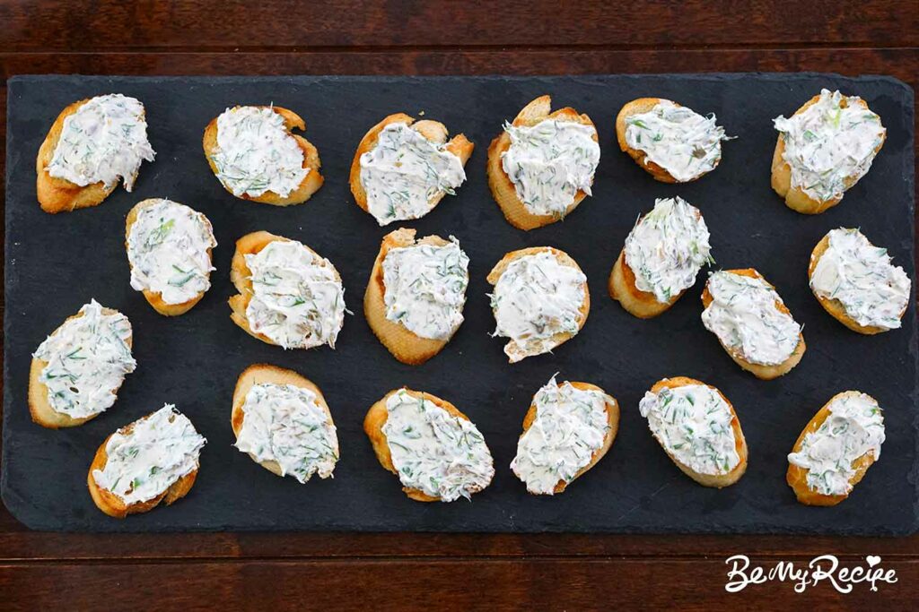 Topping the crostini with cream cheese