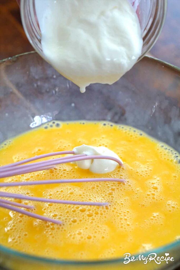 Adding cream/yogurt to the eggs to make the frittata.