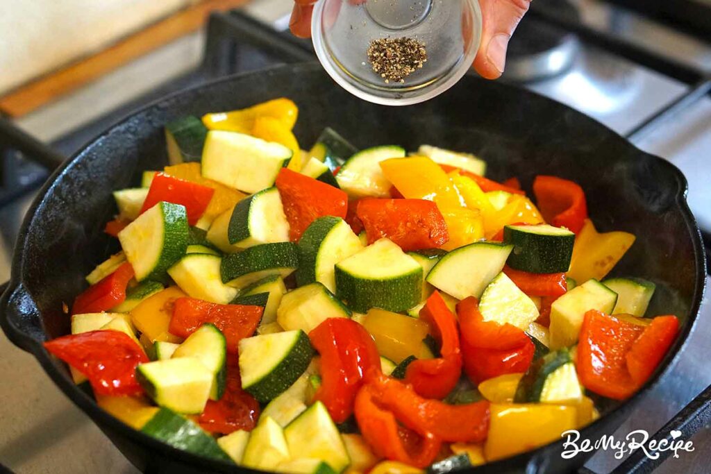 Adding black pepper to the veggies.