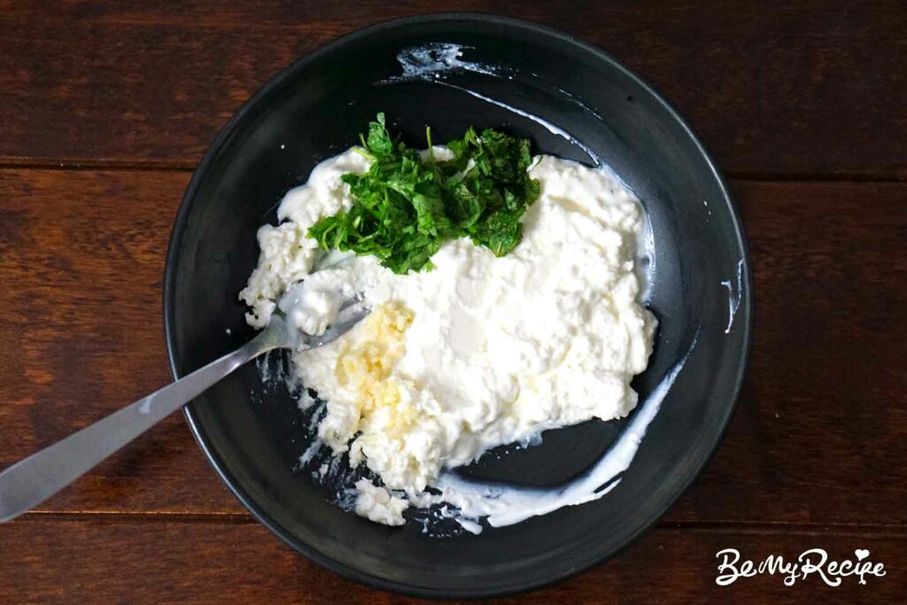 Adding garlic and herbs to the feta cheese
