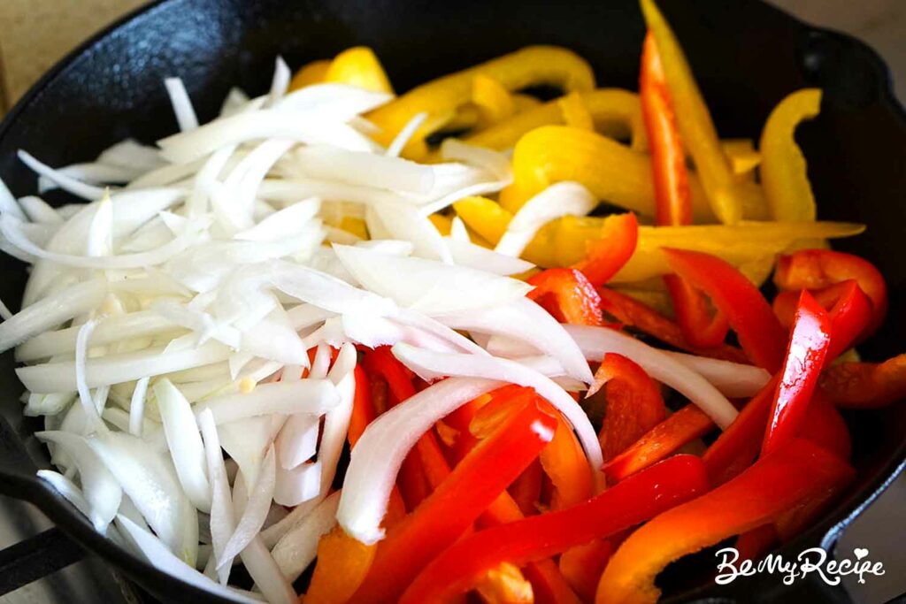 Sliced onions and bell peppers in the cast iron pan