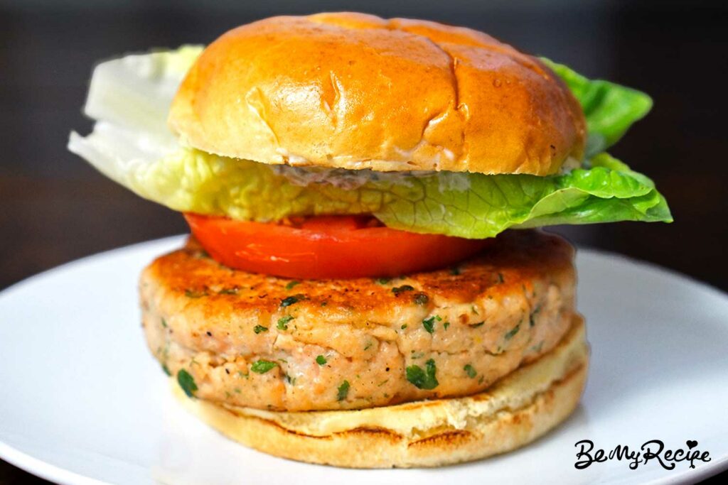salmon burger with lettuce, tomato, and mayo sauce