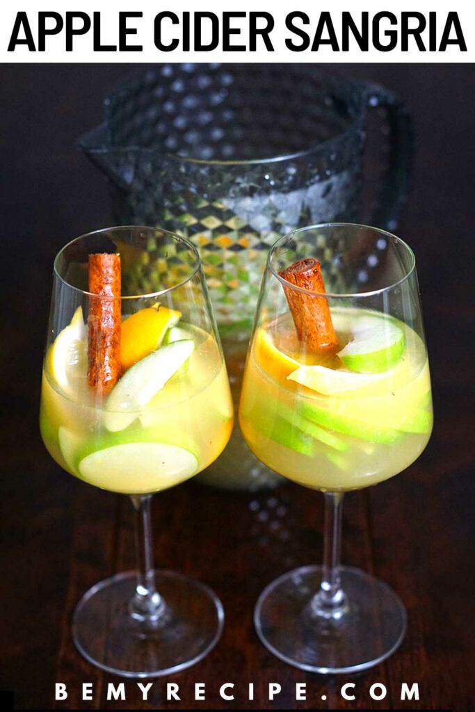 Apple Cider Sangria with Oranges, Lemons, and Cinnamon in two glasses and a pitcher (Pin)