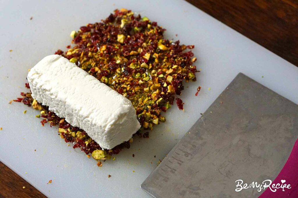 Rolling the goat cheese log in the cranberry-pistachio-honey coating.