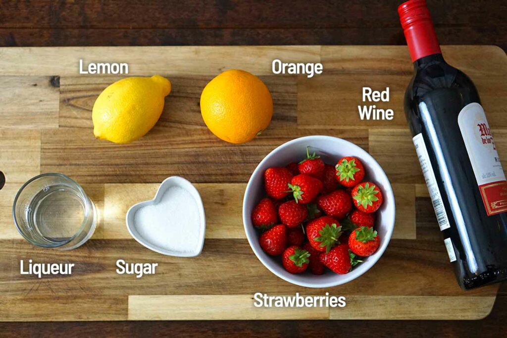 Strawberry red wine sangria ingredients on a wooden board.