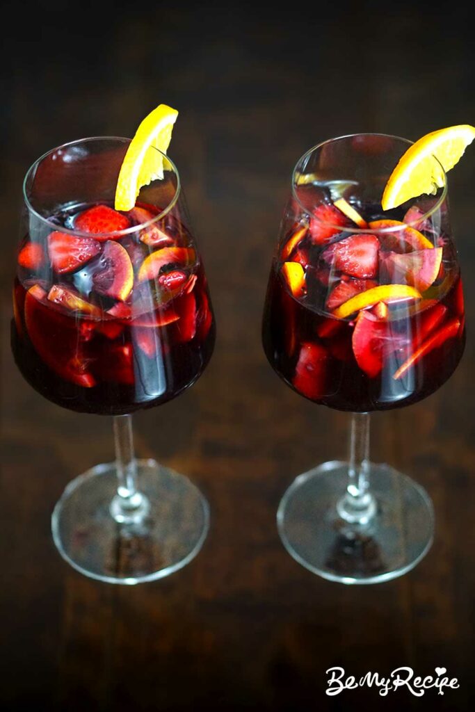 Sangria served in wine glasses with orange slices on the rim.