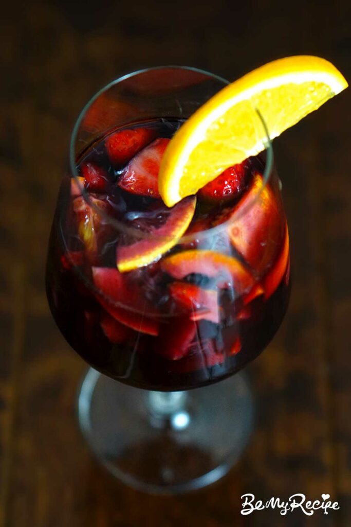 Strawberry red wine sangria with an orange slice in a glass.