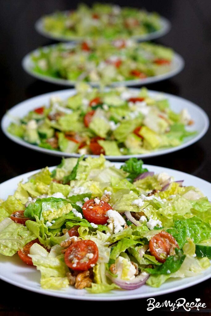 Romaine salad with feta, walnuts, cucumber, and tomatoes served on four plates