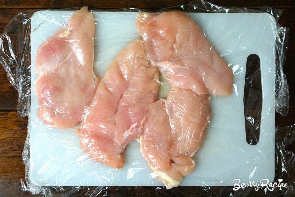 Flattening the chicken breasts on a board