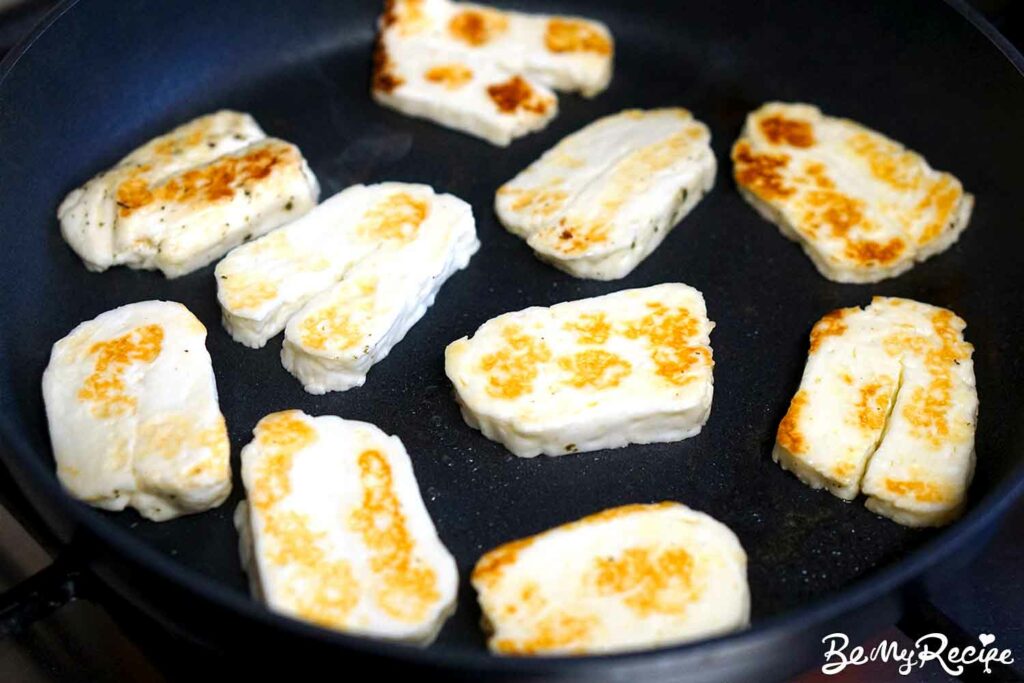 Golden halloumi slices in a skillet.