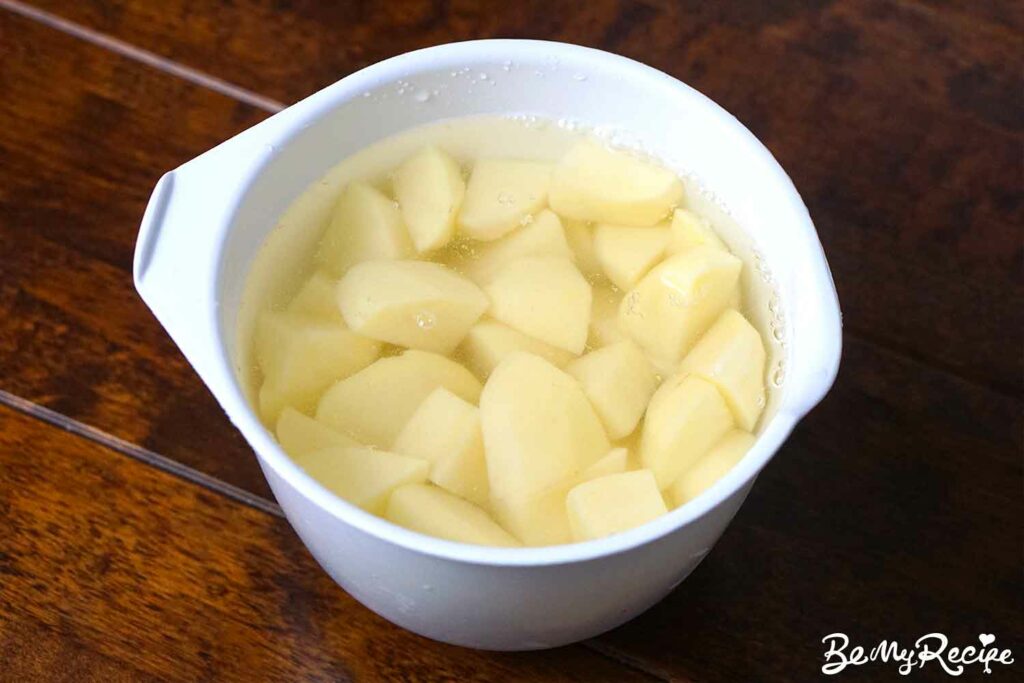Potatoes cut into bite-sized pieced (in a bowl with cold water).