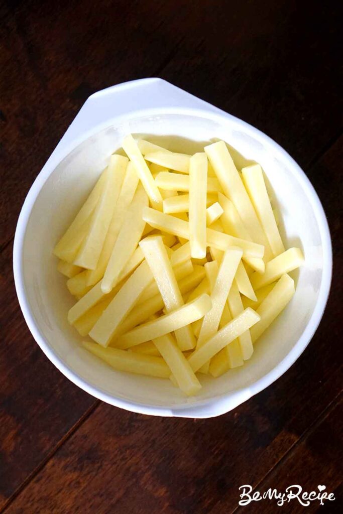 matchstick potatoes tossed with oil and salt in a round white bowl