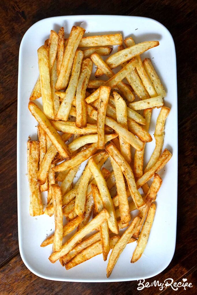 overhead view of air fryer parmesan potato fries served on a white rectangular platter