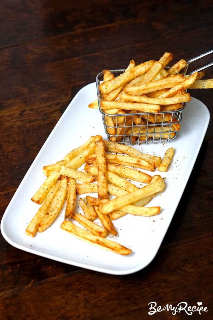 air fryer fries served part in a metal basket and the remaining laid out on a white rectangular plate, ready to be eaten