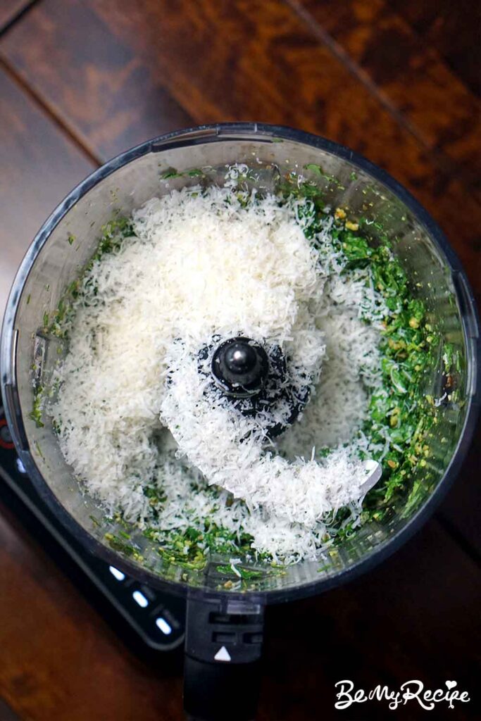 Adding the grated Parmesan to the basil and nuts