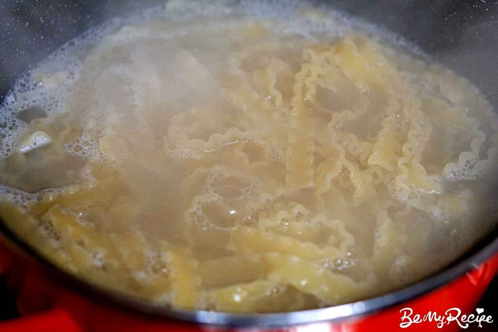 Boiling the pasta in a large pot on the stove.