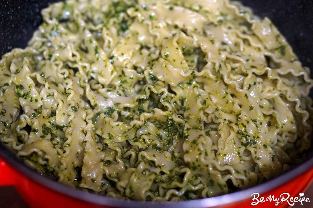 Tossing the cooked pasta with the pesto and pasta water.