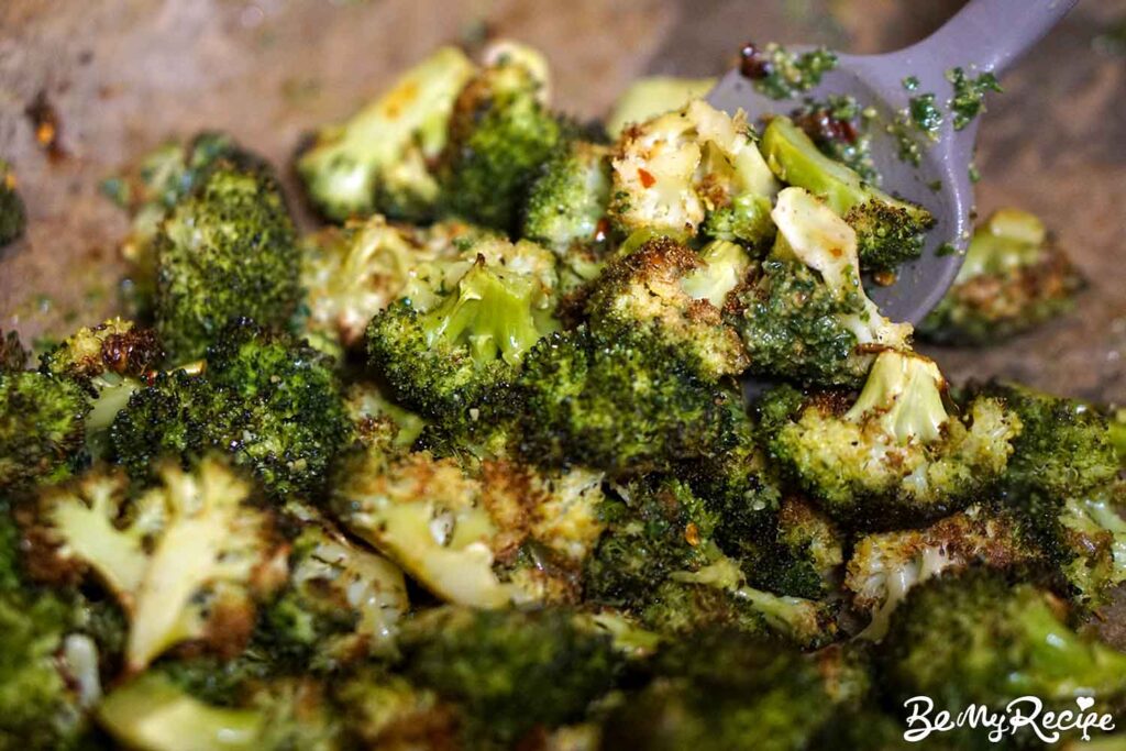 Tossing the roasted broccoli with lemon juice, lemon zest, and pesto.