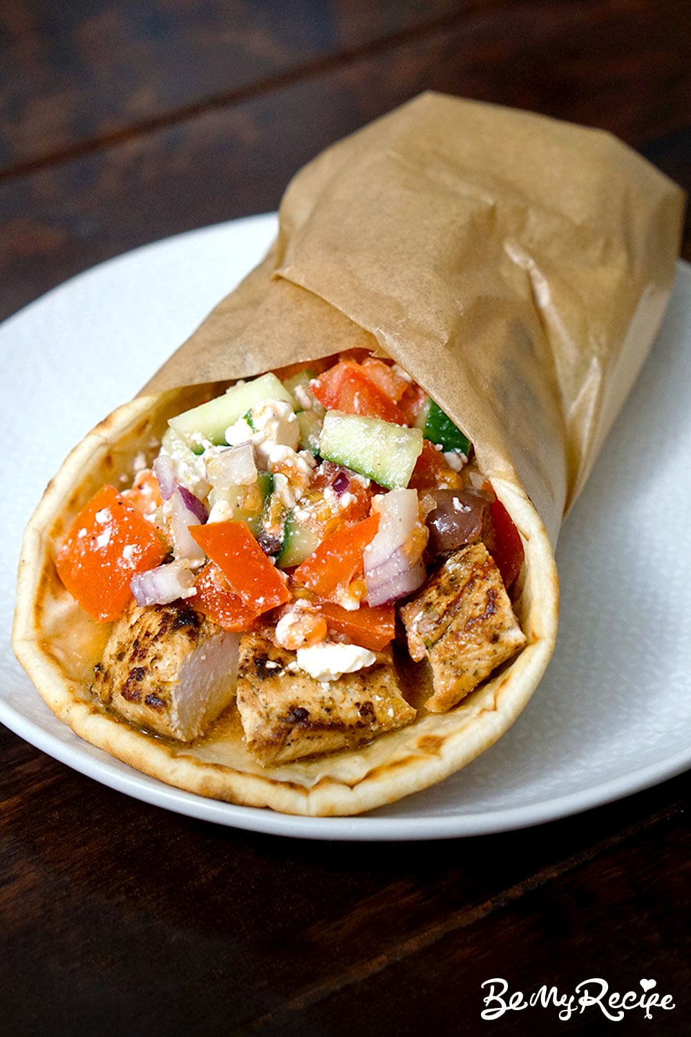 close up of chicken Greek salad flatbread wrap served on a white plate showing the filling of the wrap